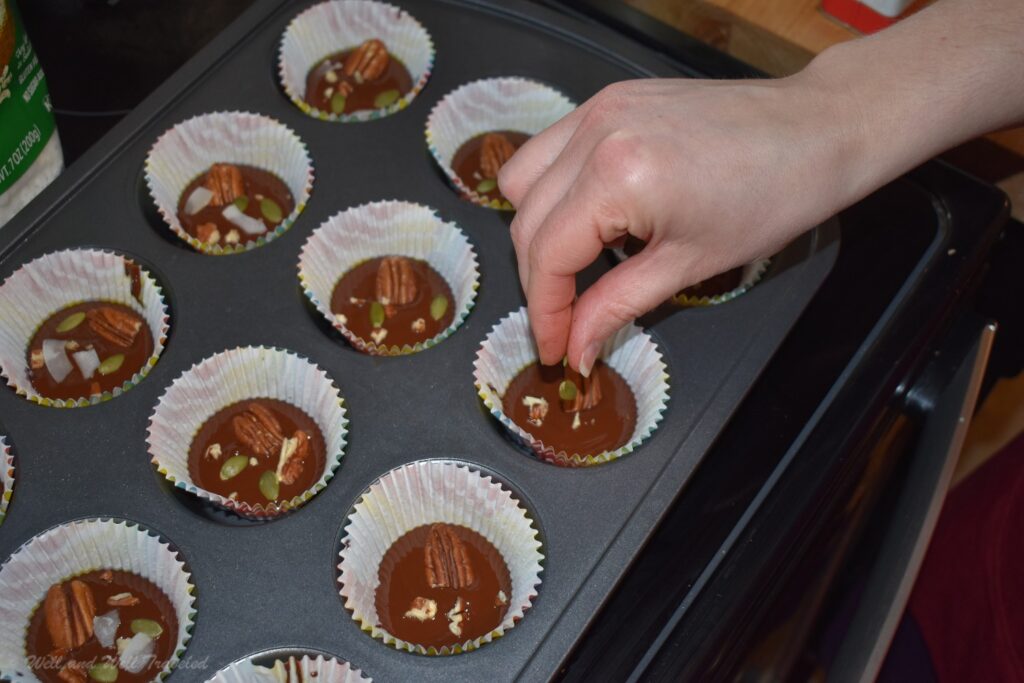 Putting the seeds and nuts in the chocolate treat in cupcake liners