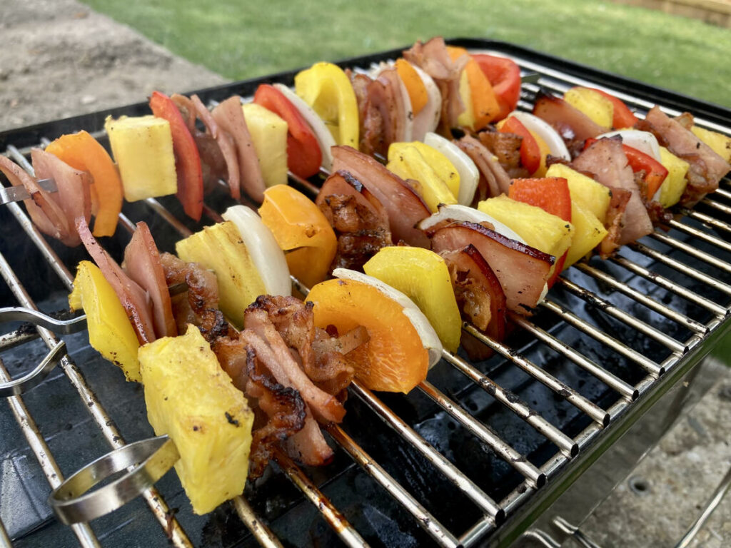 Paleo Hawaiian Skewers with ham, pineapple, onions, and bell peppers on a grill