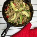 Spicy Paleo Egg Breakfast with avocado on top and a red oven mitt to the side.