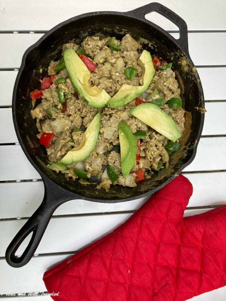Spicy Paleo Egg Breakfast with avocado on top and a red oven mitt to the side.