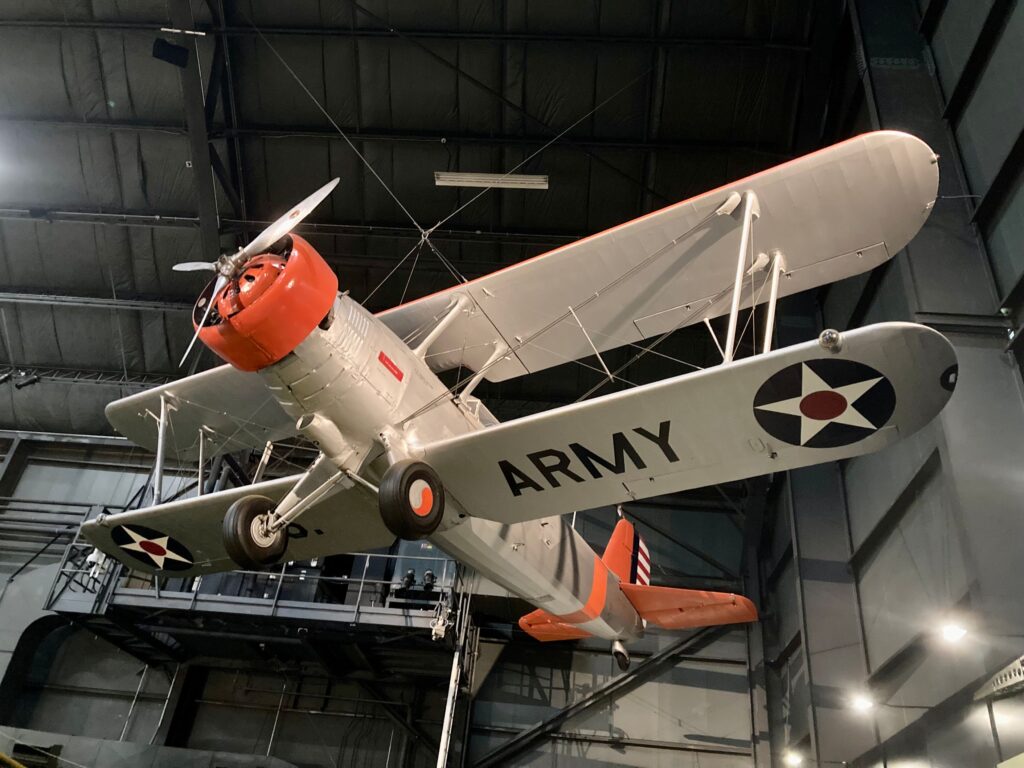 An early military plane painted gray and orange suspended from the ceiling at the National Air Force Museum