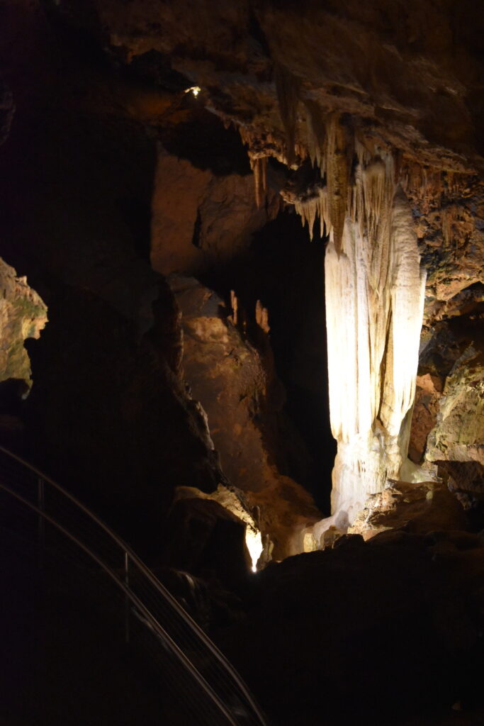 A photo of Pluto's Ghost, a very white figure among darker cave formations