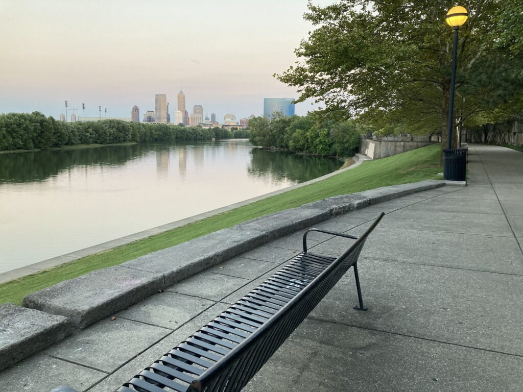 A pathway along the water with the skyline of Indianapolis in the distance.