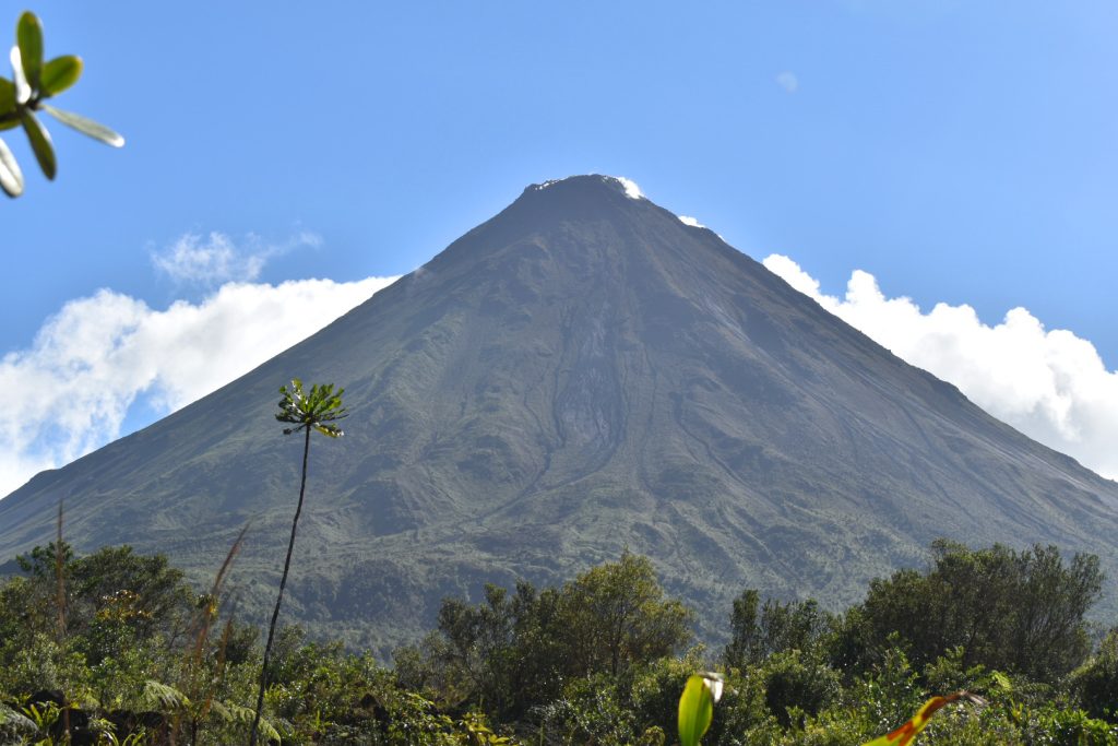 A close view of a volcano with blue sky and clouds above