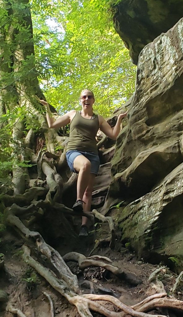 A woman hiking the Ice Box at Turkey Run State Park, walking down a steep hill with lots of big tree roots