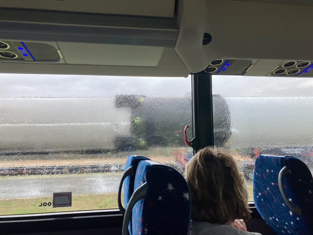 A view out of the NASA bus tour of the SpaceX Falcon 9 rocket on a truckbed beside the bus