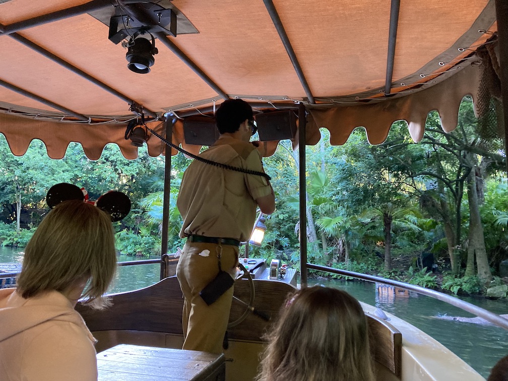 A family on Disney's Jungle Cruise Ride with the skipper speaking into a speaker in front of them
