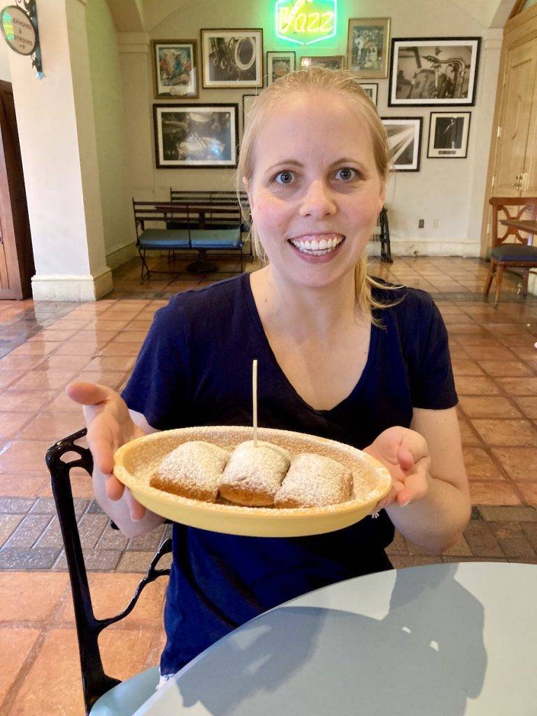 A woman holding up a plate of gluten-free beignets at Disney World